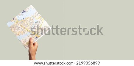 Banner with hand raising map. Travelling, trip routes study, tourism concept on grey background. Copy space. High quality photo