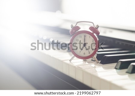 Alarm clock on piano background. Music lesson