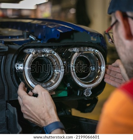 Car headlight in repair close-up. The car mechanic installs the lens in the headlight housing. The concept of a car service.Installation of LED lenses in the headlight. LED lens.Restoration of optics. Royalty-Free Stock Photo #2199066601