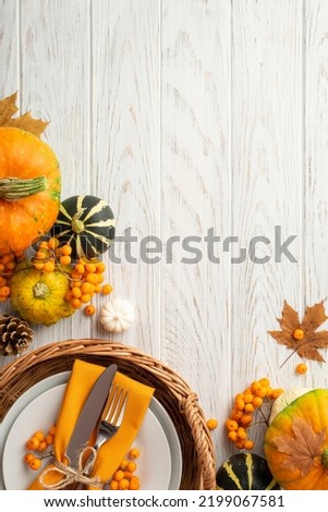 Thanksgiving day concept. Top view vertical photo of rattan basket with plate knife fork napkin pumpkins pattypan pine cone maple leaves rowan on isolated white wooden table background with copyspace