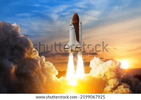 Spaceship lift off. Space shuttle with smoke and blast takes off into space on a background of sunset. Successful start of a space mission. Elements of this image furnished by NASA. Royalty-Free Stock Photo #2199067925