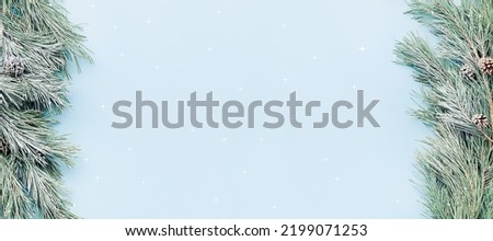 festive Christmas background - fir branches in the snow on the sides of the banner, on a blue background, copy space