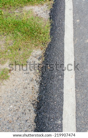 asphalt texture on the road on day time with grass and rock