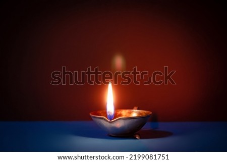 Happy Diwali. Traditional symbols of Indian festival of light. Burning diya oil lamps and flowers on red background. Copy space. Royalty-Free Stock Photo #2199081751