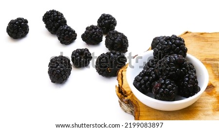 Blackberries in a white plate on a wooden board. Close-up
