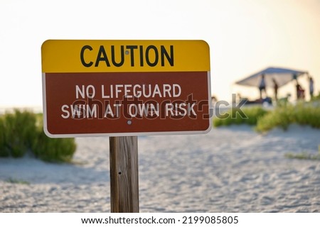 Warning sign poster on sea side beach saying that there is no lifeguard on duty