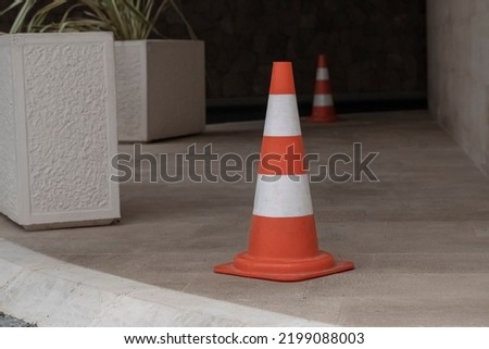 an old battered orange road cone stands on the road enclosing a parking place within the city limits. Road regulation tools that have deteriorated from exploitation.