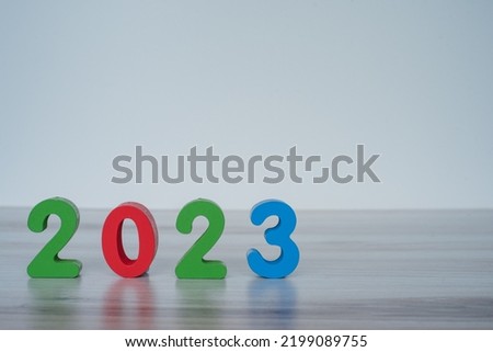 2023 standing colored block numbers on light wooden and white background. Left focused.