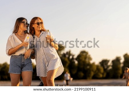 Two girls on river beach walking and talking
Red head girl 
Summer time stock photo