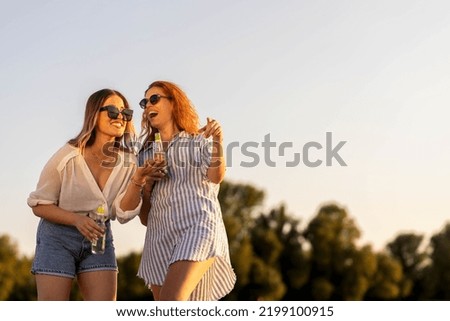 Two girls on river beach walking and talking
Red head girl 
Summer time stock photo