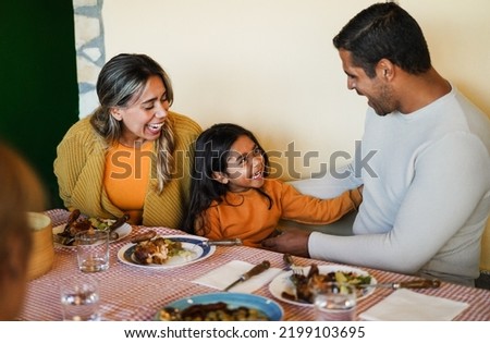 Latin parents having fun with their daughter during home dinner - Focus on little girl face