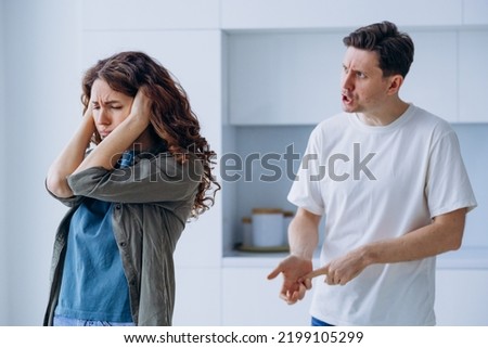 Curly-haired woman plugs ears in stress not wanting to hear angry husband quarrel shout and argue about family problems closeup Royalty-Free Stock Photo #2199105299