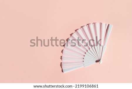 White fan on a pastel background. Minimal creative concept of menopause and female hot flashes. Copy space, flat lay