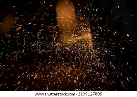 Sparks from grinder. Metal cutting. Bright lights in dark. Industrial background. Details of steel production.