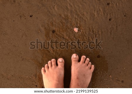 a pair of women's feet on the textured beach sand