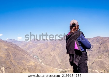 Elderly Caucasian woman calling on a cell phone on top of a mountain.