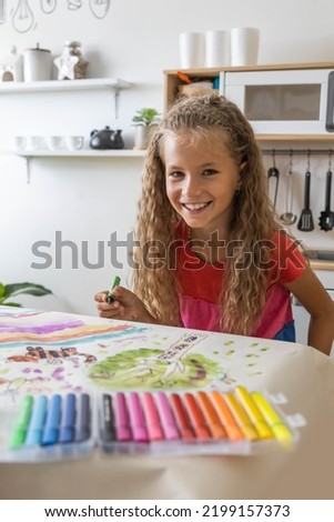 Laughing blonde curly barefoot little girl drawing paper art picture multicolored chalks sitting floor near childish hovel. Relaxed female kid happy childhood preschool early development entertainment Royalty-Free Stock Photo #2199157373