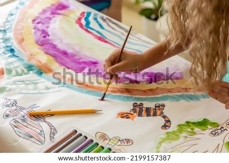 Laughing blonde curly barefoot little girl drawing paper art picture multicolored chalks sitting floor near childish hovel. Relaxed female kid happy childhood preschool early development entertainment Royalty-Free Stock Photo #2199157387