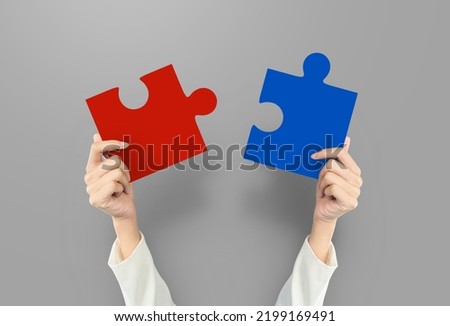 Hands holding jigsaw red and blue at grey background. Business strategy concept. jigsaw teamwork concept.