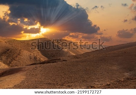 Sunset in the desert and sun rays spreading. Beautiful dramatic clouds on gold sky. Golden sand dunes in desert in Judean desert, Israel. Sunny sky over cliffs, large salt mountains Sodom and Gomorrah Royalty-Free Stock Photo #2199172727