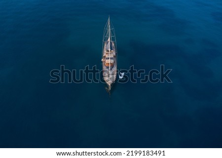 Wooden classic big gulet yacht is anchored on dark blue water. top view. Large wooden sailing gulet yacht anchored aerial view. Expensive wooden sailing yacht in classic style top view. Royalty-Free Stock Photo #2199183491