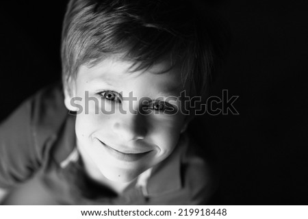 A close up portrait of a handsome smiling little boy, black-and-white photo 