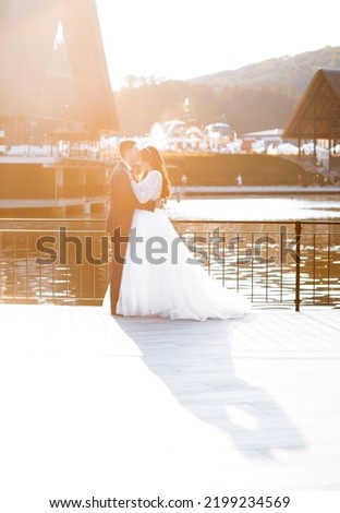 Newlyweds in love pose by the lake at sunset.
