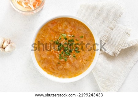 Cabbage (sauerkraut) soup in bowl over white stone background. Top view, flat lay
