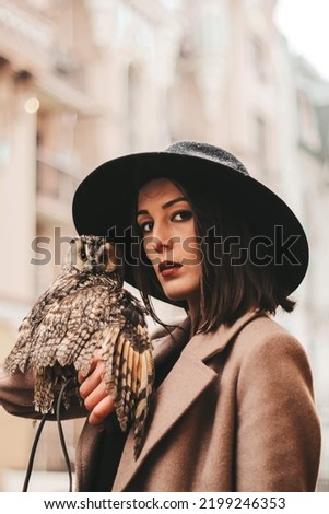 very beautiful girl in a hat with an owl. High quality photo