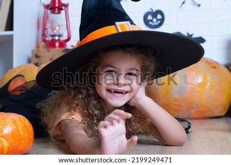Funny child girl in witch costume for Halloween with pumpkin