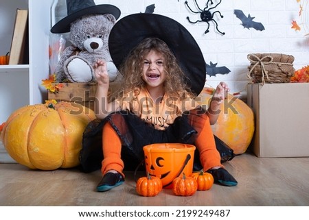 Funny child girl in witch costume for Halloween with pumpkin