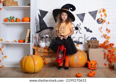 Happy child girl in costume witch for Halloween with pumpkins 