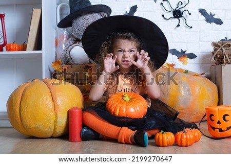 Happy child girl in costume witch for Halloween with pumpkins 