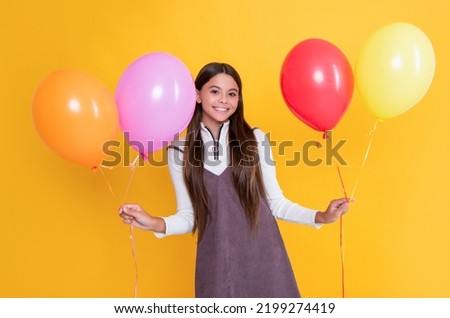 glad child with party colorful balloons on yellow background