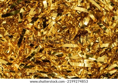 Golden shiny tinsel ribbons. Golden sequins, sparkling stripes of serpentine. Festive decor for new year, birthday, party. Background for the holiday. Heap of glowing tinsel close up. Top view. Royalty-Free Stock Photo #2199274853