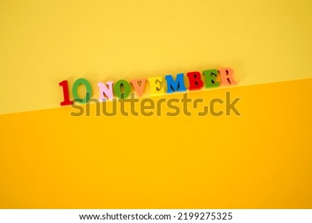 November 10 on a yellow, paper background with multicolored and wooden letters with space for text. The concept of the world science day.