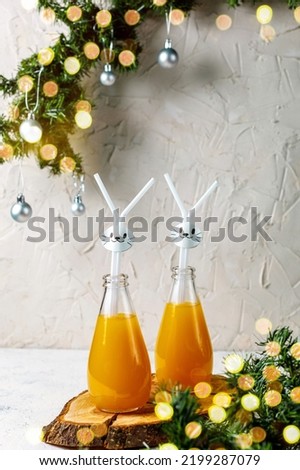 Orange drink decorated with white rabbit on light background for children party with bokeh. Christmas funny food concept for kids