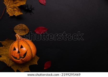 Layout on the theme of the autumn Halloween holiday, funny pumpkins and yellow leaves, copy the space on the side. Toy Jack lantern on a black background