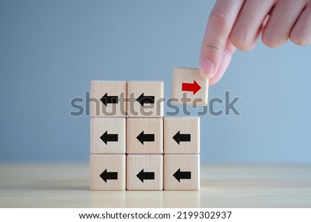 Hand holding red arrow that opposite direction black arrow. Individuality, Think outside the box, Think difference. Business disruption and leadership.	
