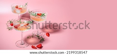 refreshing fruit cocktail. Glasses with cold pink champagne or punch with wine strawberries on pink background. Long banner format. place for text.