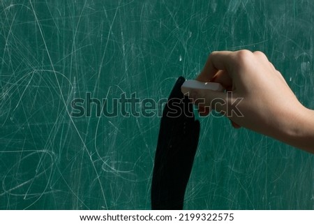 Hand with chalk. Blank green schoolboard, chalk board as background