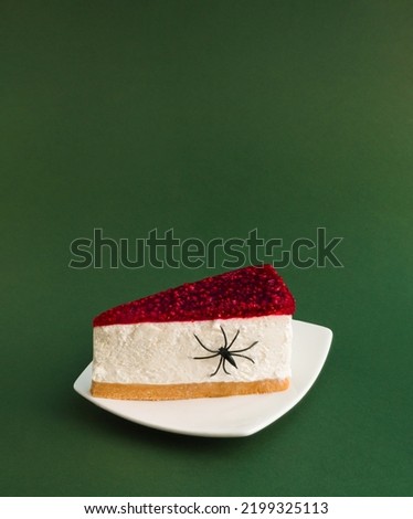 Creative Halloween minimal concept with cheesecake and spider on dark green background. Spooky holiday food concept. Copy space.