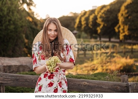 A beautiful young girl in a long dress holds a bunch of grapes against the backdrop of nature. Winery advertisement. Vineyards. Girl on the background of beautiful nature Royalty-Free Stock Photo #2199325933
