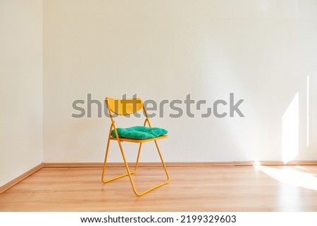Folding chair with pillows in front of wall in a room in an empty apartment Royalty-Free Stock Photo #2199329603