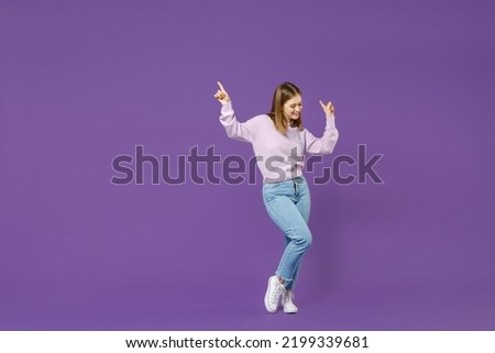 Full length young overjoyed excited joyful smiling happy student caucasian woman in purple sweater dancing point finger up with isolated on violet background studio portrait People lifestyle concept