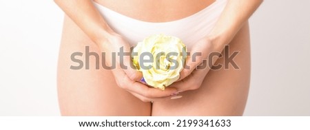 Caucasian woman in white panties with white rose flower on a uniform background, closeup