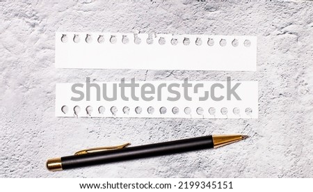 On a marble background, two torn strips of white paper with space for inserting text and a black pen. Copy space