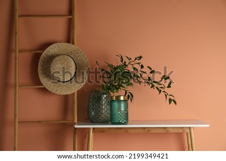 Stylish decorative vases on table near wall Royalty-Free Stock Photo #2199349421
