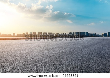 Asphalt road and modern city skyline with buildings scenery at sunset Royalty-Free Stock Photo #2199369611