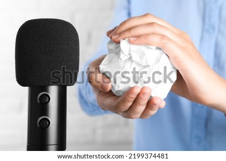 Woman making ASMR sounds with microphone and crumpled paper, closeup
